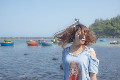 Woman in sunglasses tousling hair at beach