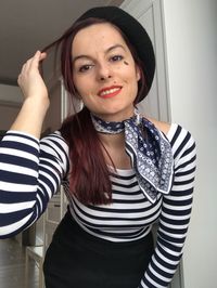 Portrait of smiling woman wearing scarf and flat cap at home