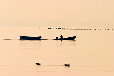 Silhouette person on sea against sky during sunset