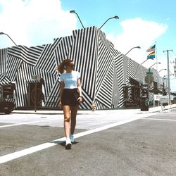 Full length of woman standing on street against sky