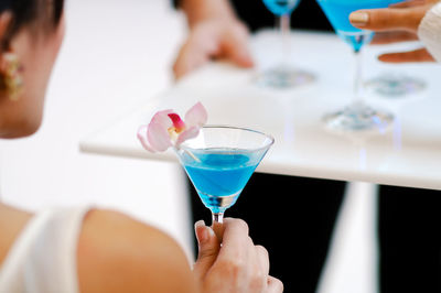 Midsection of woman drinking glass on table