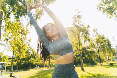 Young woman standing against trees