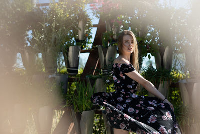 Young woman smiling while standing by plants