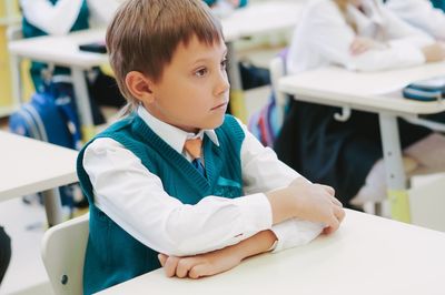 Child in school uniform at lesson in classroom