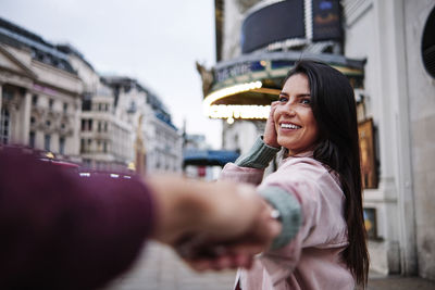 Portrait of smiling young woman standing in city