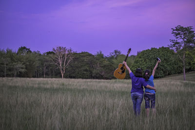 Rear view of man standing on field against sky