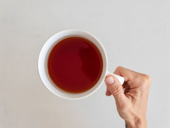 Midsection of person holding tea cup against white background