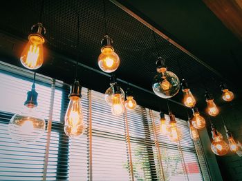 Low angle view of illuminated light bulbs hanging from ceiling