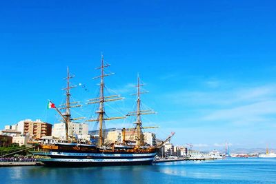 Boats in harbor against clear blue sky