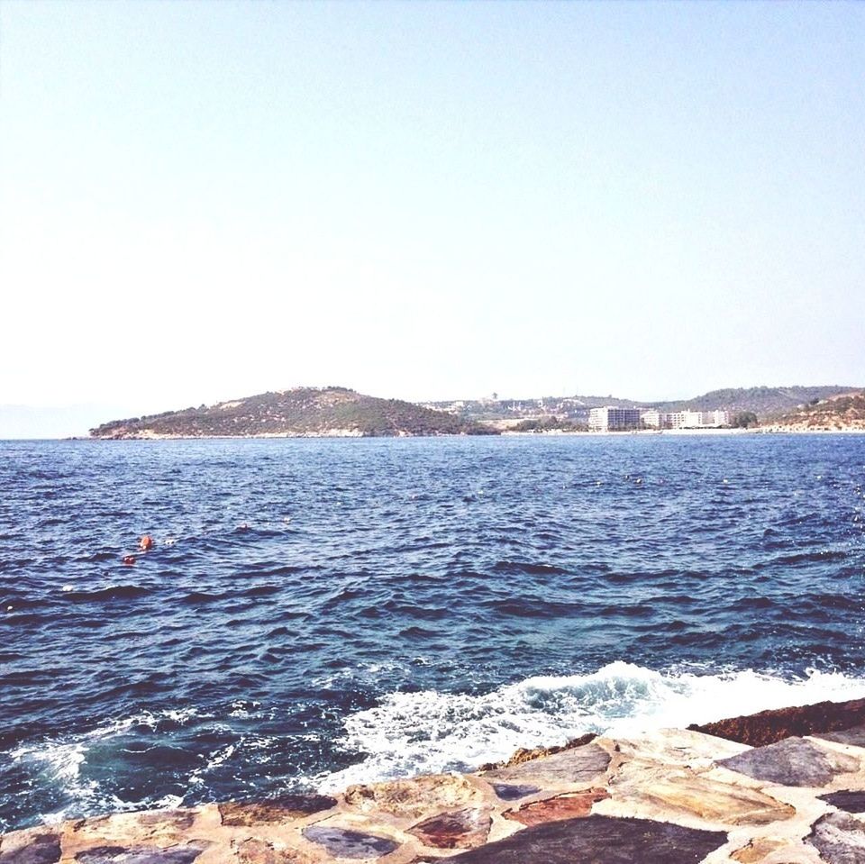 water, sea, clear sky, copy space, scenics, tranquil scene, tranquility, beauty in nature, mountain, nature, rippled, rock - object, blue, idyllic, day, waterfront, wave, coastline, shore, outdoors