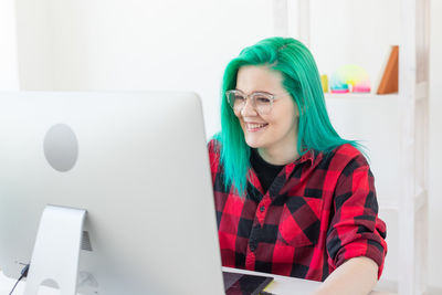 Portrait of young woman using phone while sitting on table