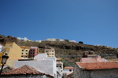 Houses in town against clear blue sky