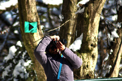 Man photographing on tree trunk