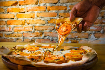 Midsection of person holding pizza on table
