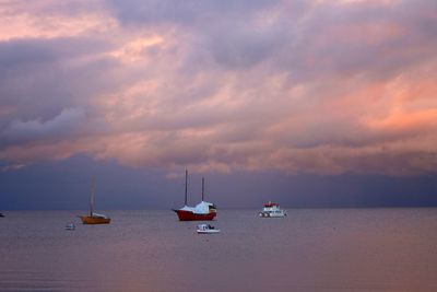 Boats on sea against cloudy sky during sunset