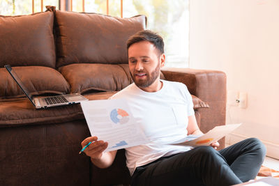 Couple using digital tablet while sitting on sofa at home