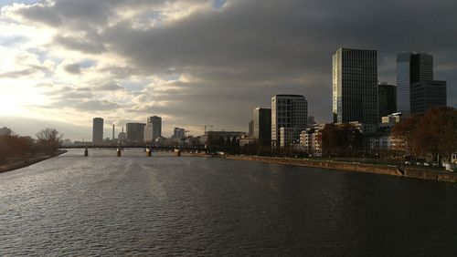 Modern buildings by river against sky in city