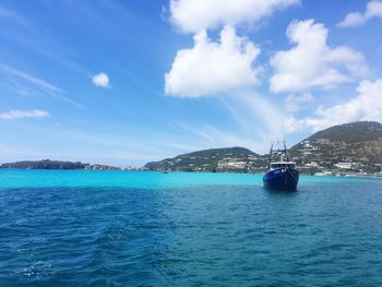 Boats in sea against cloudy sky