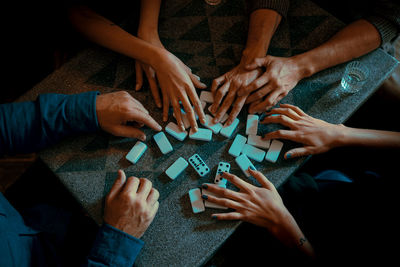 Cropped hands of friends playing dominoes on floor
