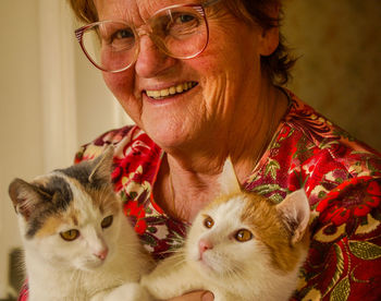 Portrait of smiling senior woman with cats at home