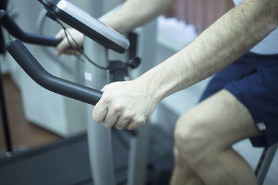 Midsection of man exercising on exercise bike at gym