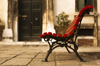 Side view of empty bench against buildings in city