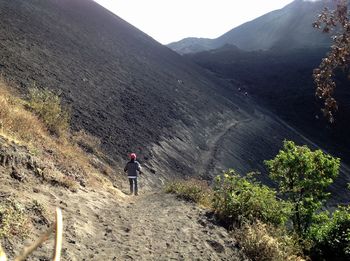 Rear view of man walking on mountain against sky