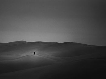 Man walking in desert against sky at dusk