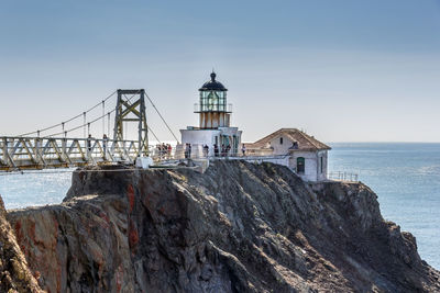 Lighthouse by sea against sky