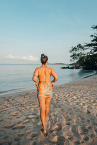 Full length of woman standing at beach against sky