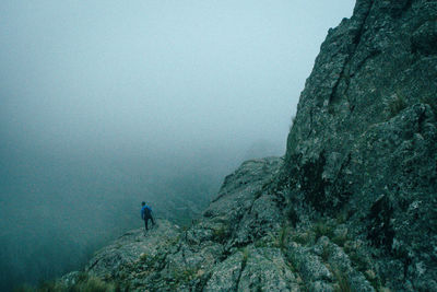 Man standing on rock against sky