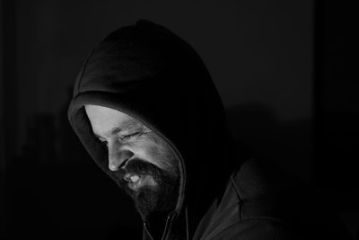 Close-up of hooded man winking against black background