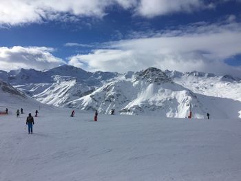 People skiing on snowcapped mountain against sky