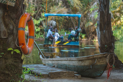 A canoe parked in the lake and a life buoy against people on a raft