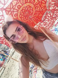 Portrait of beautiful woman wearing sunglasses while holding umbrella