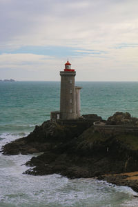 Lighthouse by sea against sky