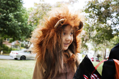 Cheerful girl in halloween costume standing on pathway during trick or treating