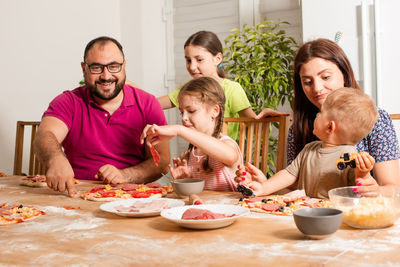 Cheerful family preparing pizza at home