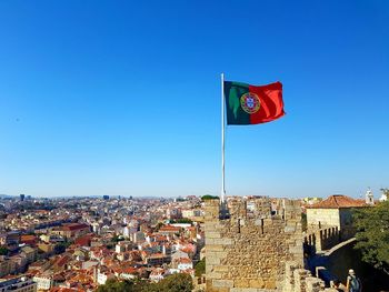 Portuguese flag waving on sao jorge castle against cityscape