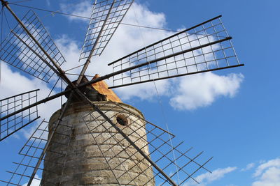 Low angle view of traditional windmill against cloudy blue sky on sunny day