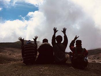 People sitting on field against sky