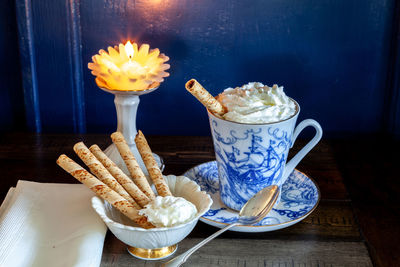Gourmet hot chocolate and whip cream in a nautical china mug with cookies on a rustic table 