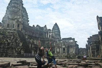 People at temple pointing against sky