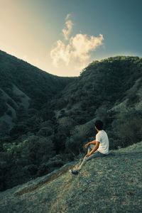 Side view of man looking at mountains against sky during sunset