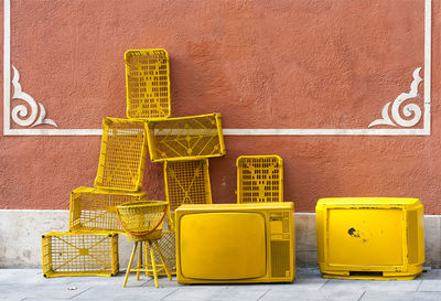 Painted yellow crates and television sets arranged against wall