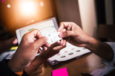 High angle view of business people holding jigsaw pieces on table