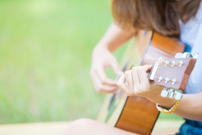 Midsection of woman playing guitar on field