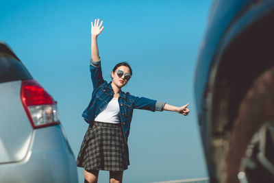 Woman with arms raised standing against sky