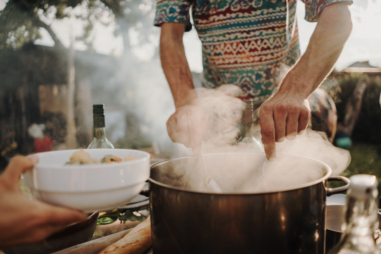 MIDSECTION OF MAN PREPARING FOOD ON BARBECUE GRILL