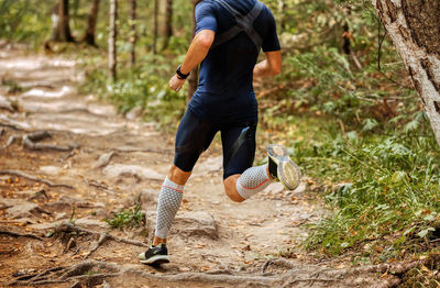Low section of man running in forest